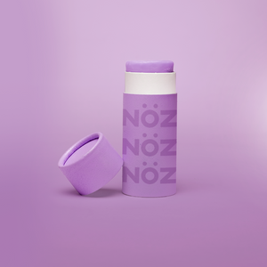 close up of the purple Noz face sunscreen stick with the cap off of it, all in front of a purple background