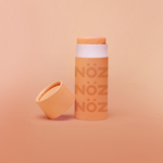 Load image into Gallery viewer, close up of the orange Noz face sunscreen stick with the cap off of it, all in front of a orange background
