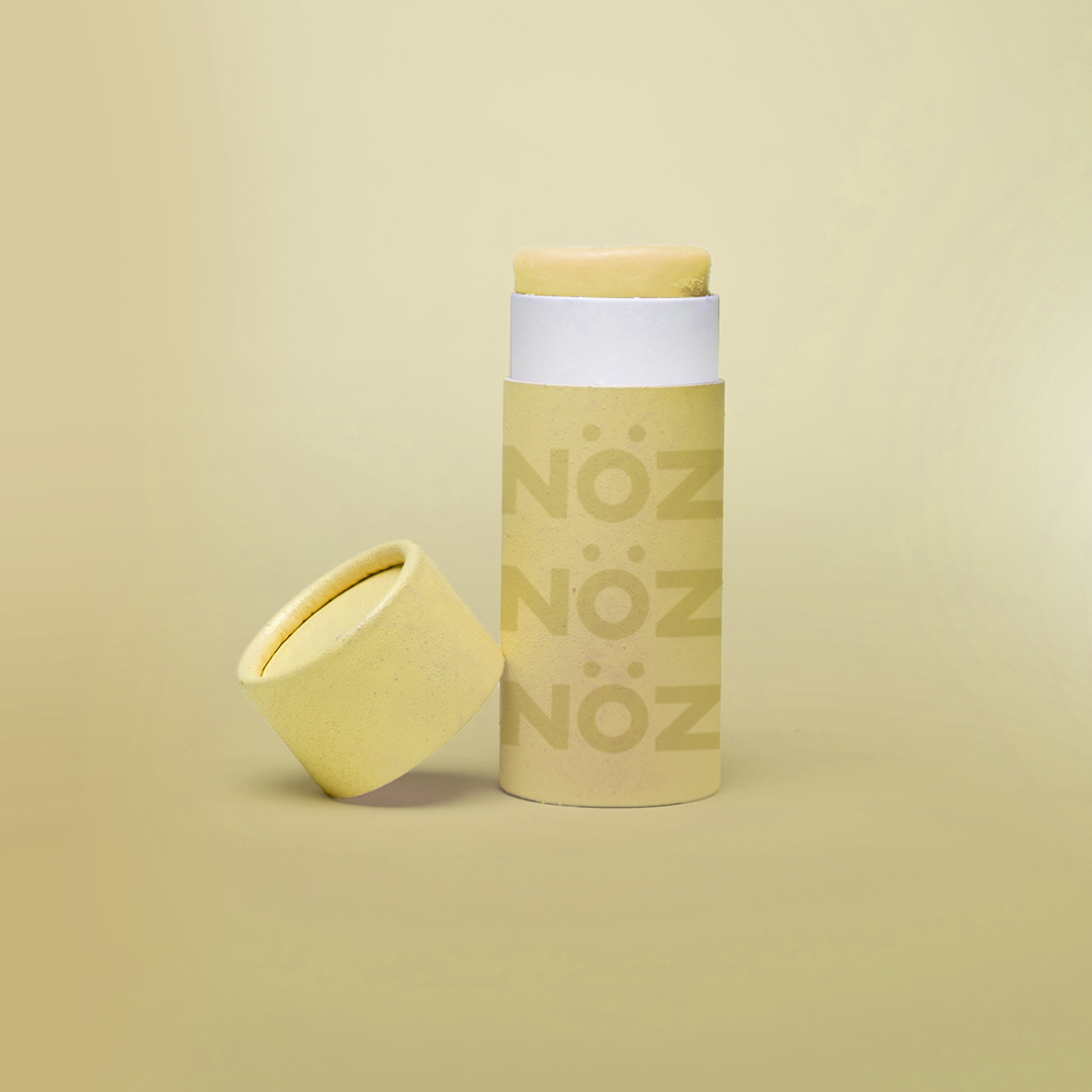 close up of the yellow Noz face sunscreen stick with the cap off of it, all in front of a yellow background