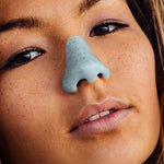 Load image into Gallery viewer, close up view of a womans neutrally posed face with bright blue sunscreen on her nose
